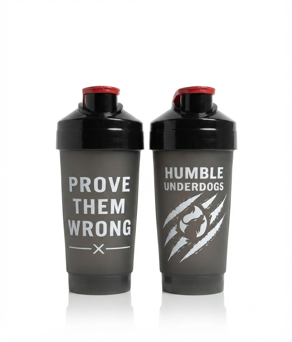 Two dark gray shaker bottles with black caps and red lids, standing side by side on a white background. The left bottle has the text 'PROVE THEM WRONG' in white, and the right bottle has 'HUMBLE UNDERDOGS' with a white claw graphic.
